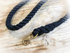 black rope dog lead with brass clip laying on timber